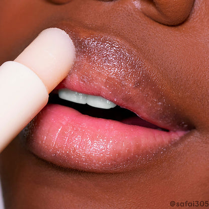 ColourPop Vanilla Lip Scrub stick exfoliating dry lips in a close-up, creamy vanilla balm gliding over the upper lip to buff flakes and reveal a glossy, hydrated finish, with the nude twist-up applicator shown in use.