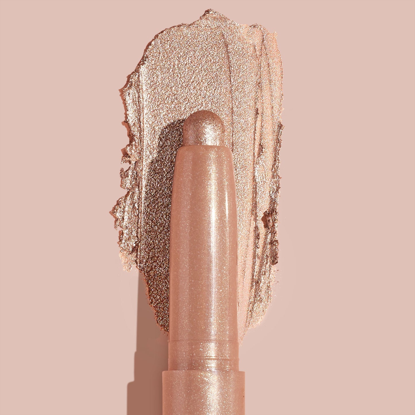 Socialite ColourPop Shadow Stix glides a metallic champagne‑rose swipe across a nude backdrop, twist‑up cream eyeshadow stick shown close up to highlight smooth, blendable texture and high‑shine shimmer for quick eyelid application.