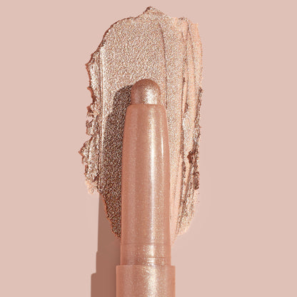 Socialite ColourPop Shadow Stix glides a metallic champagne‑rose swipe across a nude backdrop, twist‑up cream eyeshadow stick shown close up to highlight smooth, blendable texture and high‑shine shimmer for quick eyelid application.