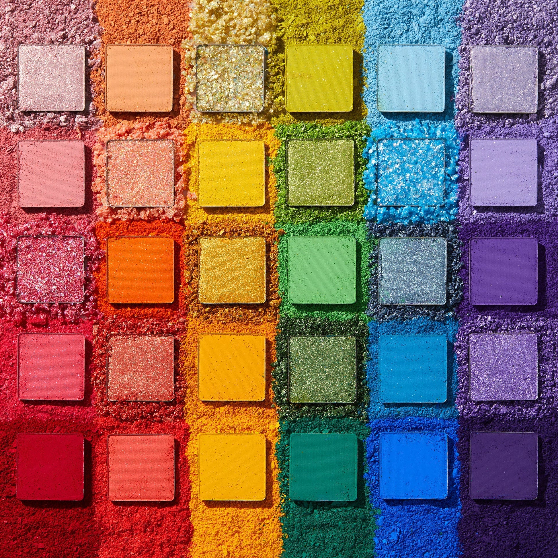 Fade Into Hue shadow palette displays 30 square pans in a rainbow grid - matte, shimmer, and pressed glitter - set on crushed pigment in a deconstructed flat lay; a vibrant ColourPop Shadow Palette.