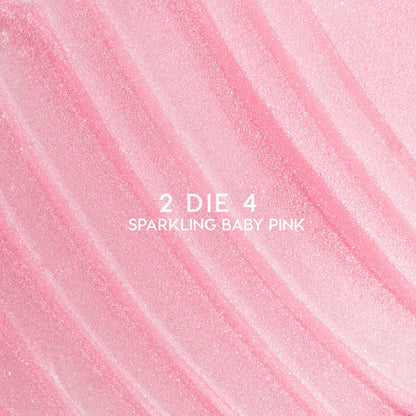 Heart to Get 2 Die 4 ultra glossy lip swatch showing sparkling baby pink shimmer in diagonal, textured streaks against a smooth pastel background, highlighting the high-shine, glittery finish for US makeup lovers.