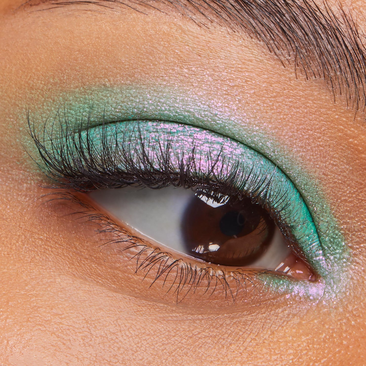 Solar Beam ColourPop Super Shock Shadow gleams on the eyelid, shifting mint green to pink-lilac, while lashes frame the close-up eye; creamy, blendable metallic finish extends from lid to inner corner for vibrant color payoff.